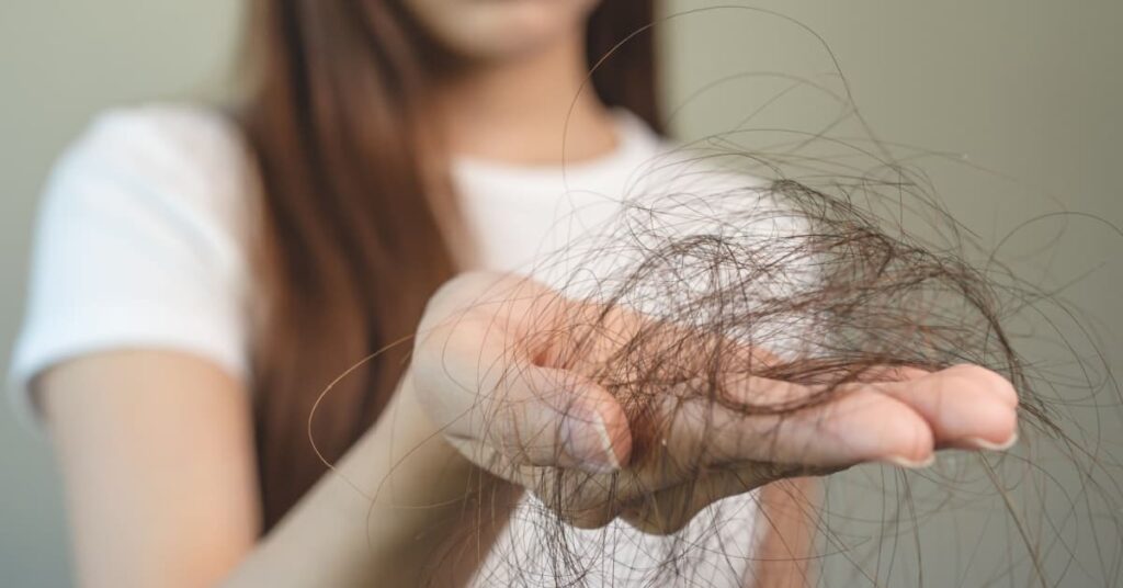 Femme montrant une poignée de cheveux qui sont tombés