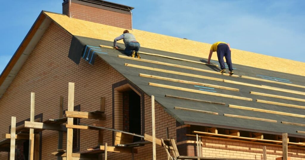 pose de sous toiture par deux hommes sur toit maison