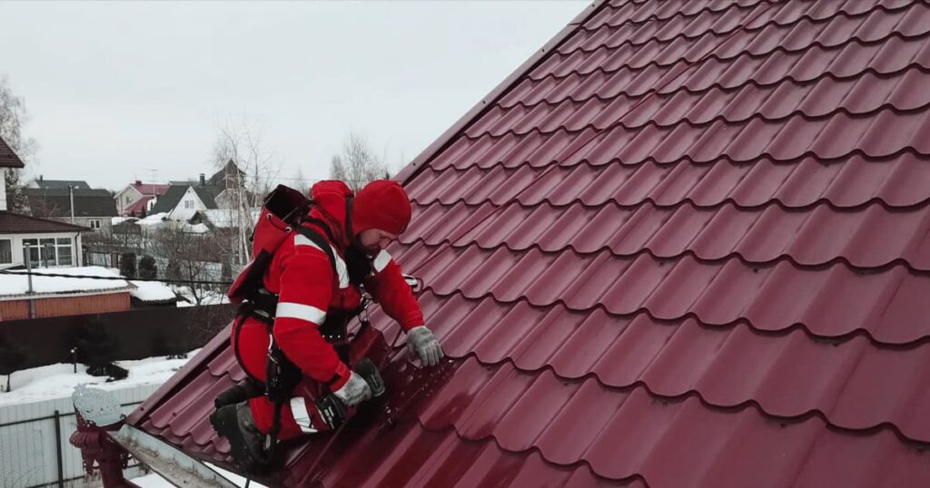 Couvreur installant des panneaux rouges en tôle imitation tuile  