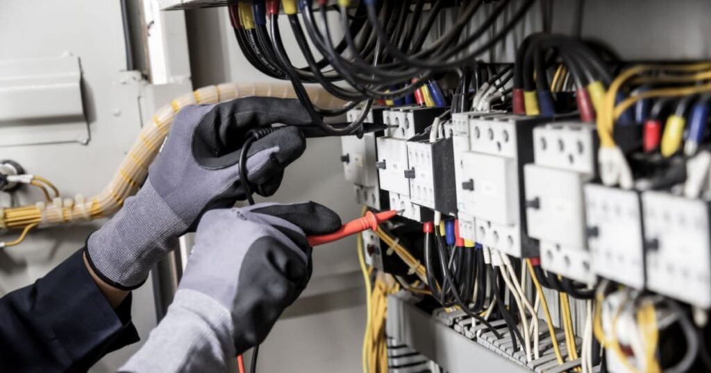 Installation d'un tableau électrique avec des gants de sécurité