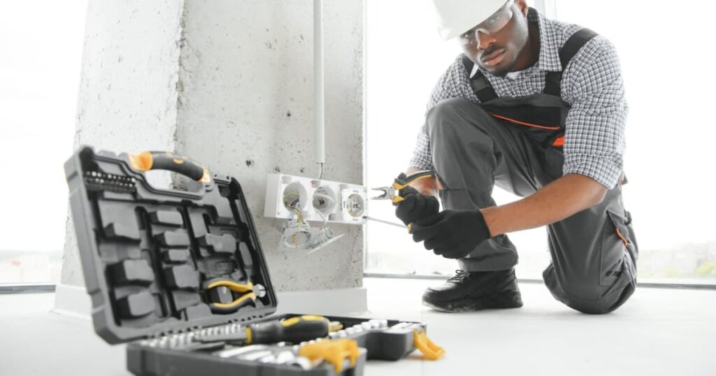 Électricien professionnel qui installe une prise sur un pilier en Béton