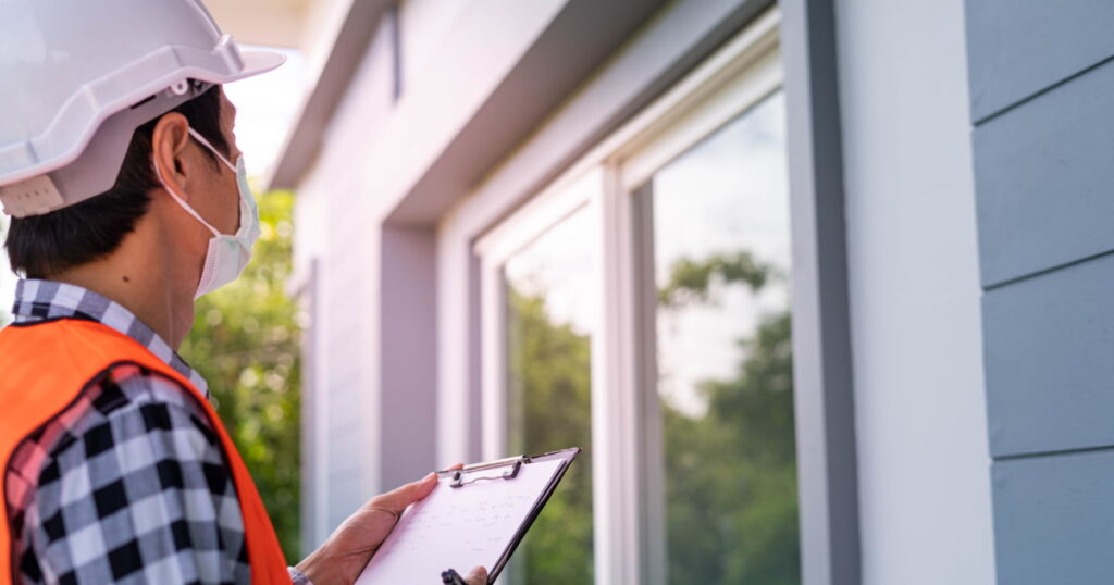 expert en stabilité  avec casque et masque de sécurité qui contrôle une maison